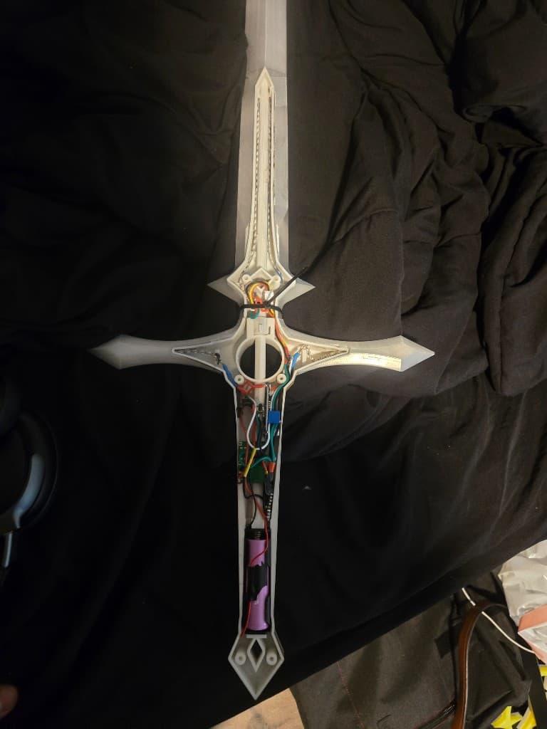 Open 3D-printed sword hilt showing ESP32-C3 wiring, LED strips, and battery pack