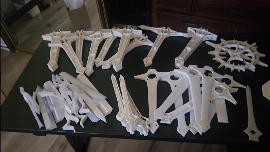 Pile of failed sword test prints and iteration parts spread across a work table