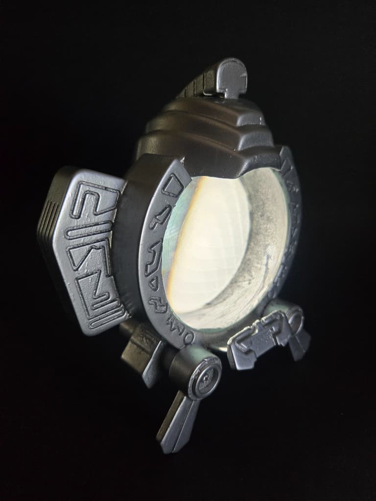 Finished Max prop with metallic silver frame, engraved glyphs, and glowing translucent lens on a black background