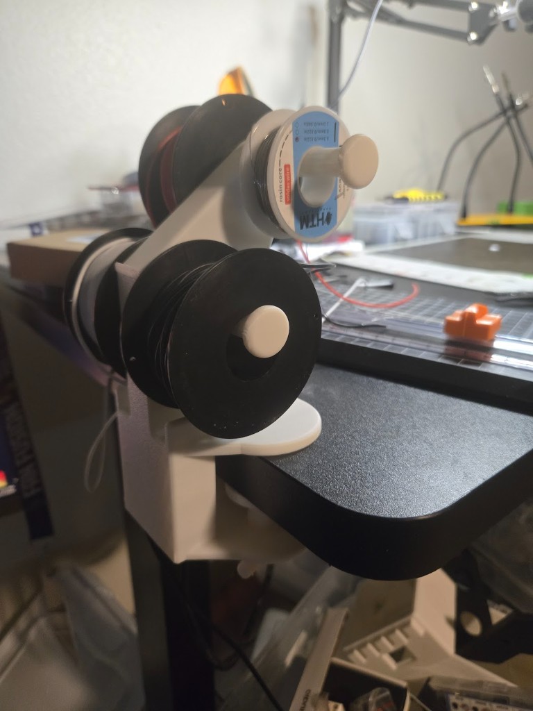 Zero-Tangle Wire Hub clamped to a workbench holding solder and wire spools